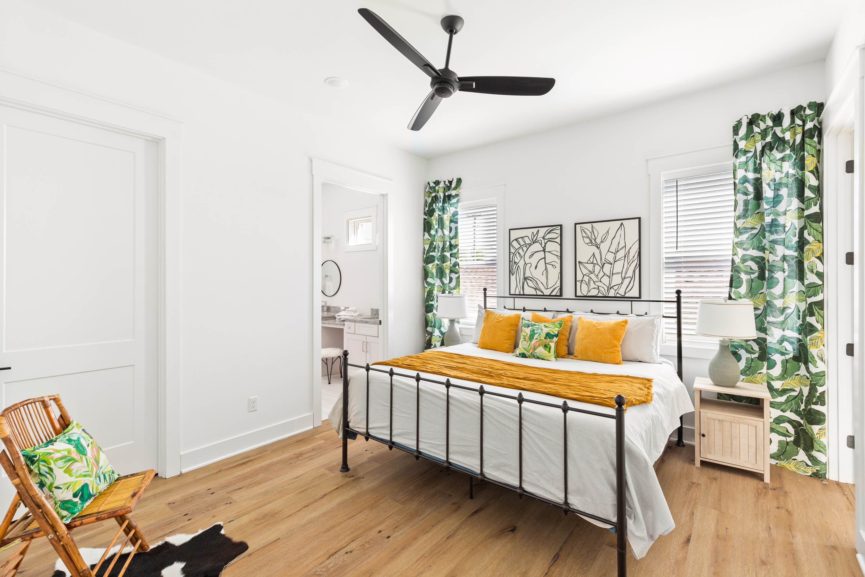 Bedroom with a metal bed frame, vibrant decor, and tropical-patterned curtains